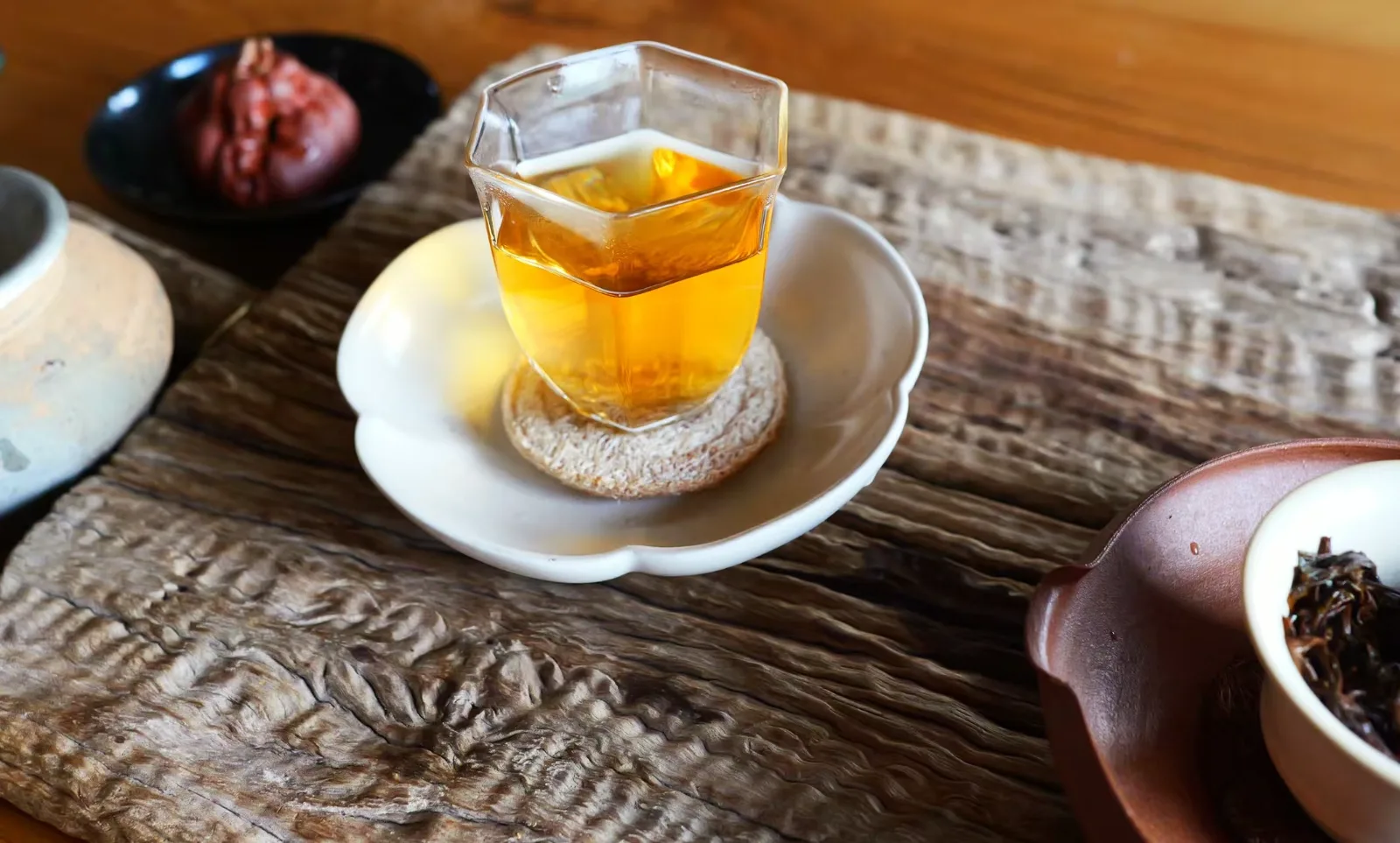 Ancestor Red brewed, clear amber liquor in a faceted glass on a weathered wooden table
