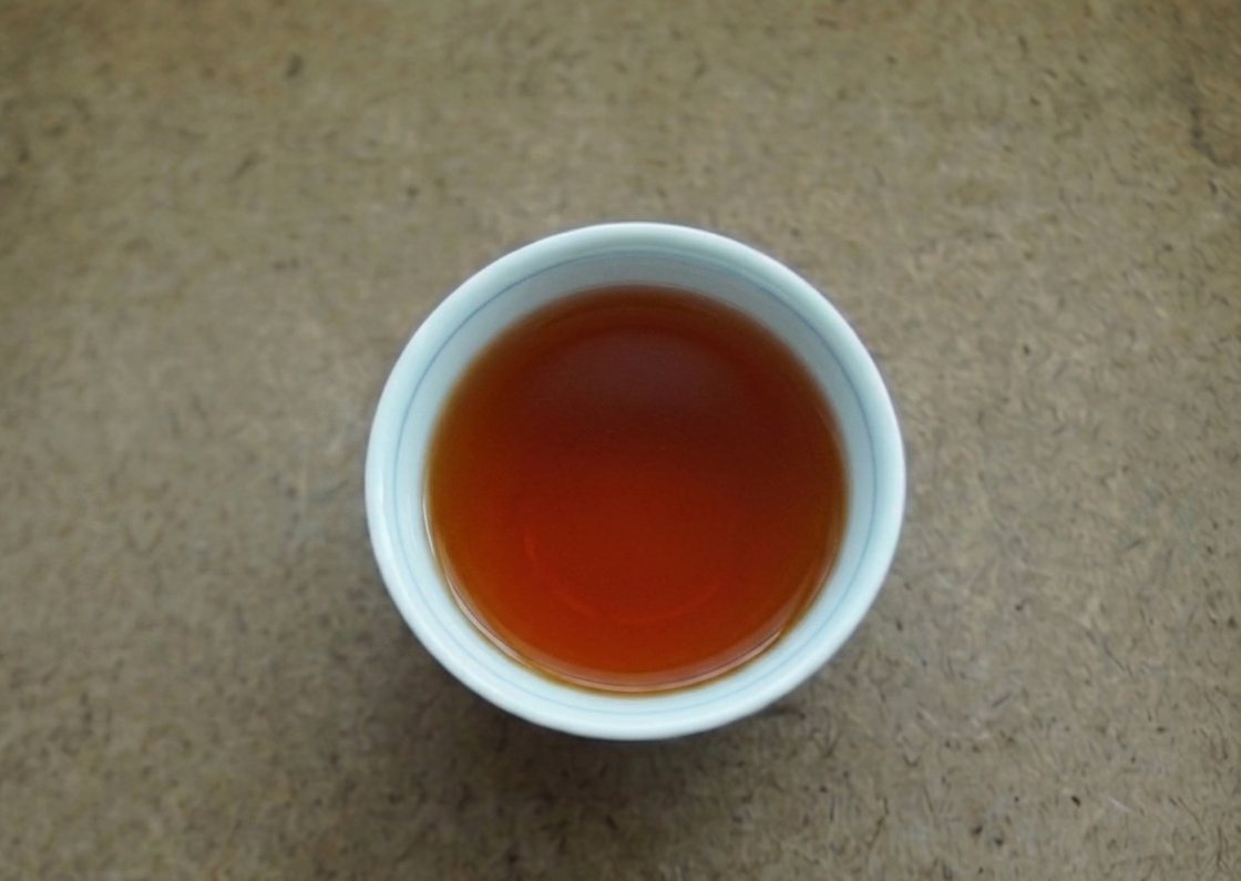 Amber liquor of aged gaoshan oolong in a white cup