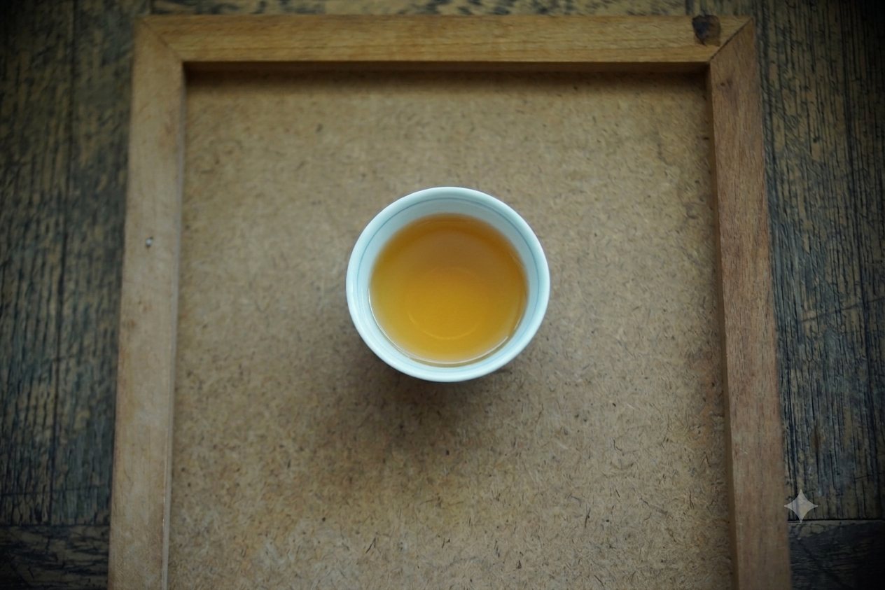 Luguanyin brewed, golden liquor in a small white cup on a wooden tray