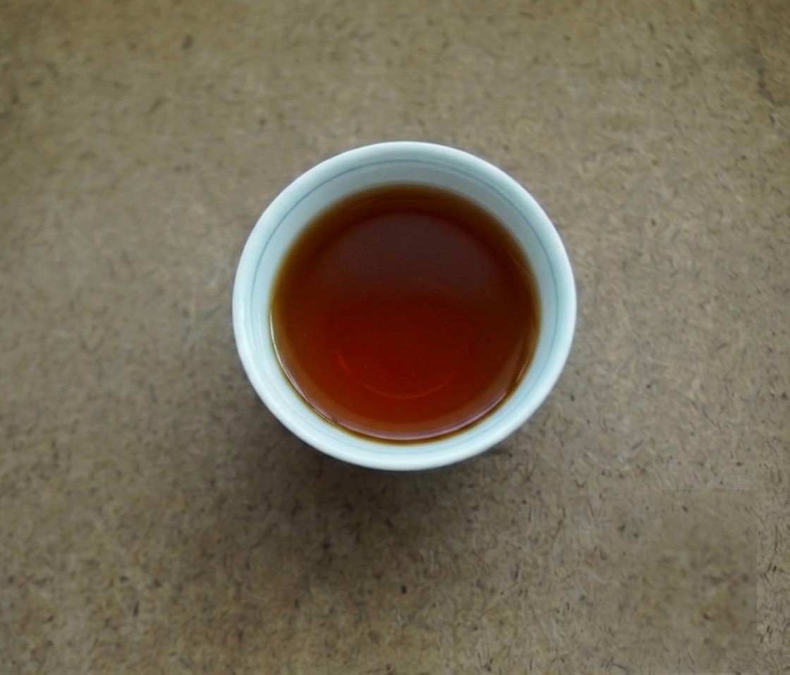 Deep red Gong Ting liquor in white cups on a wooden table