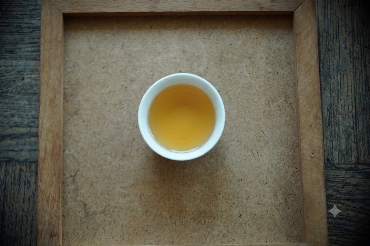 Aged Oriental Beauty brewed, amber liquor in a small white cup on a wooden tray