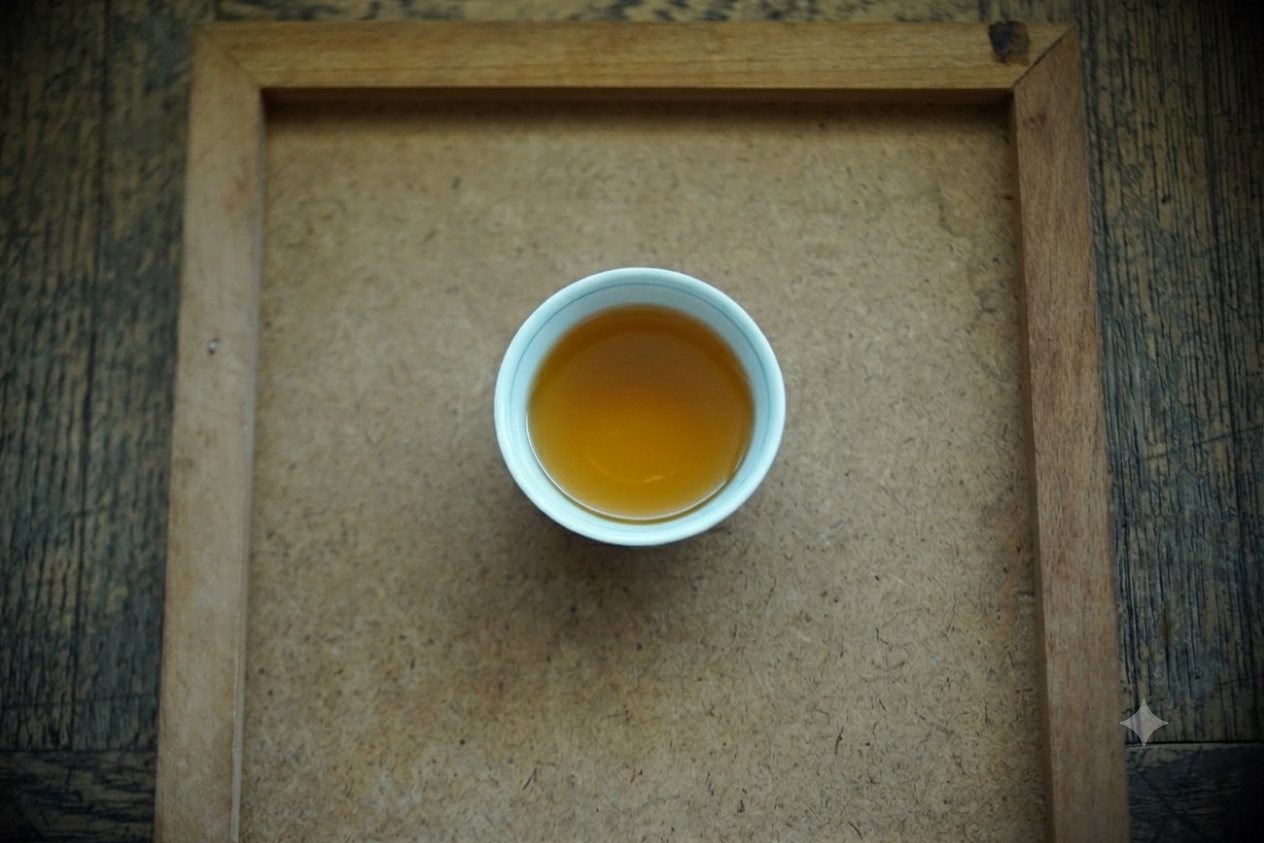 Tieguanyin brewed, pale golden liquor in a small white cup on a wooden tray