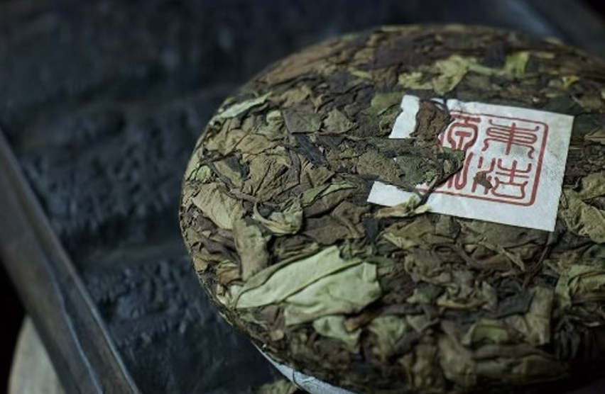 Wild white pu'erh cake with a red seal wrapper, pale pressed leaves
